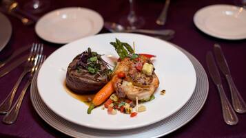 A plate of food with a steak, vegetables, and a piece of fish on a white plate.