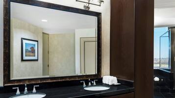 Un baño con un espejo grande, dos lavamanos y un perchero para toallas.