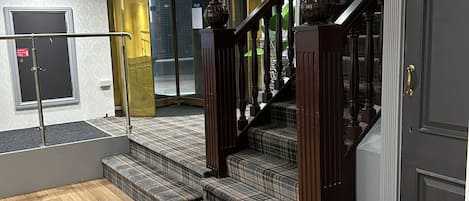 A staircase with a dark wooden handrail and carpeted steps leading to a landing.