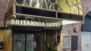 The exterior of the Britannia Hotel with a prominent entrance, a large potted plant, and a sign indicating the hotel's name.