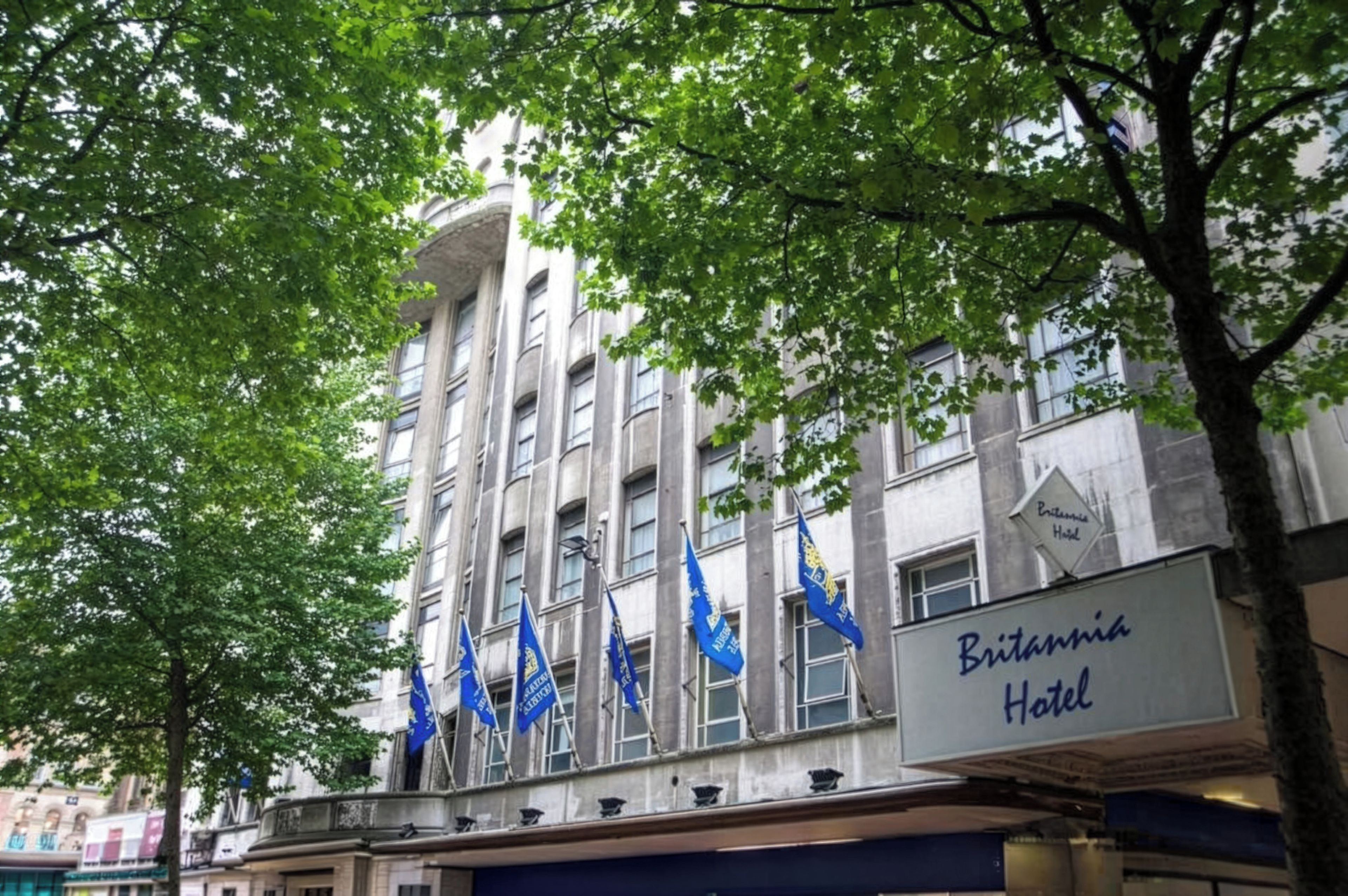 A hotel building with multiple flags and a sign indicating it is the Britannia Hotel.