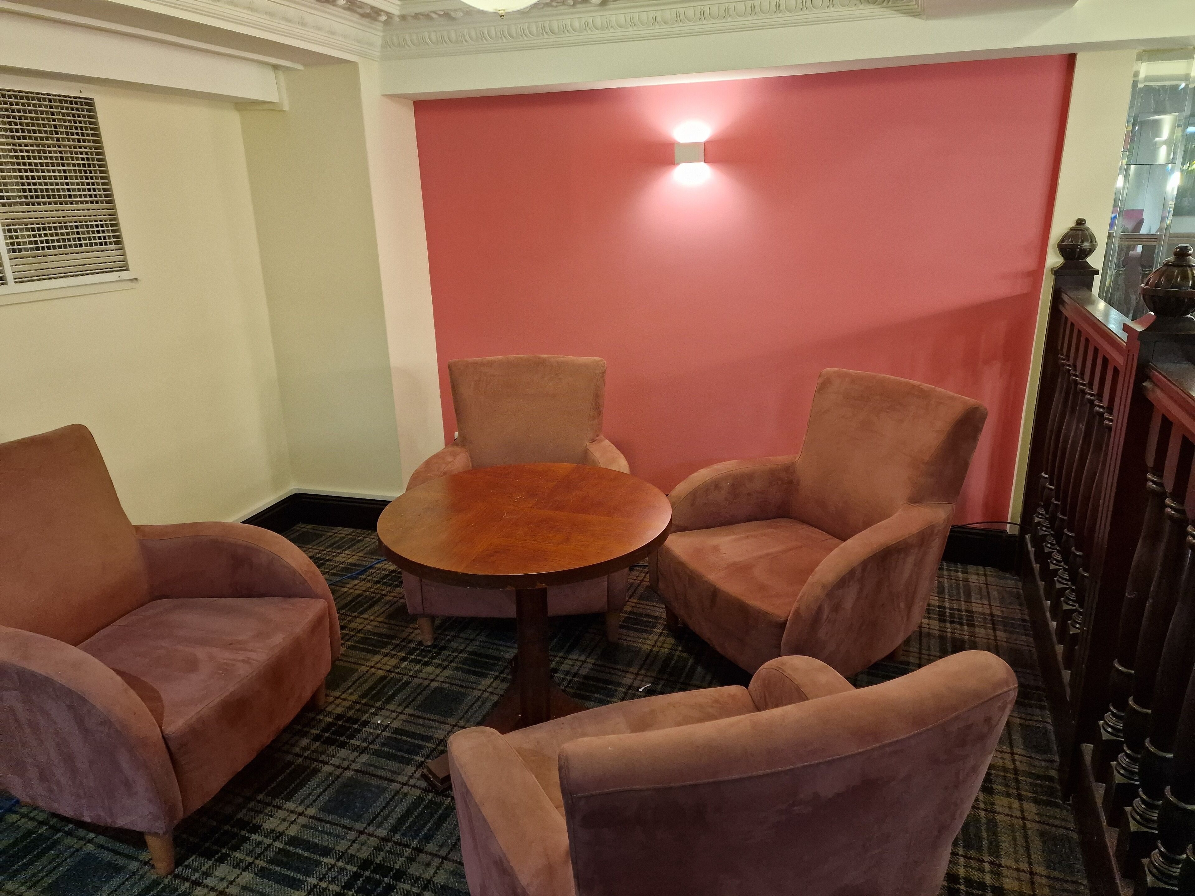A room with a plaid carpet, a round wooden table, and two armchairs.