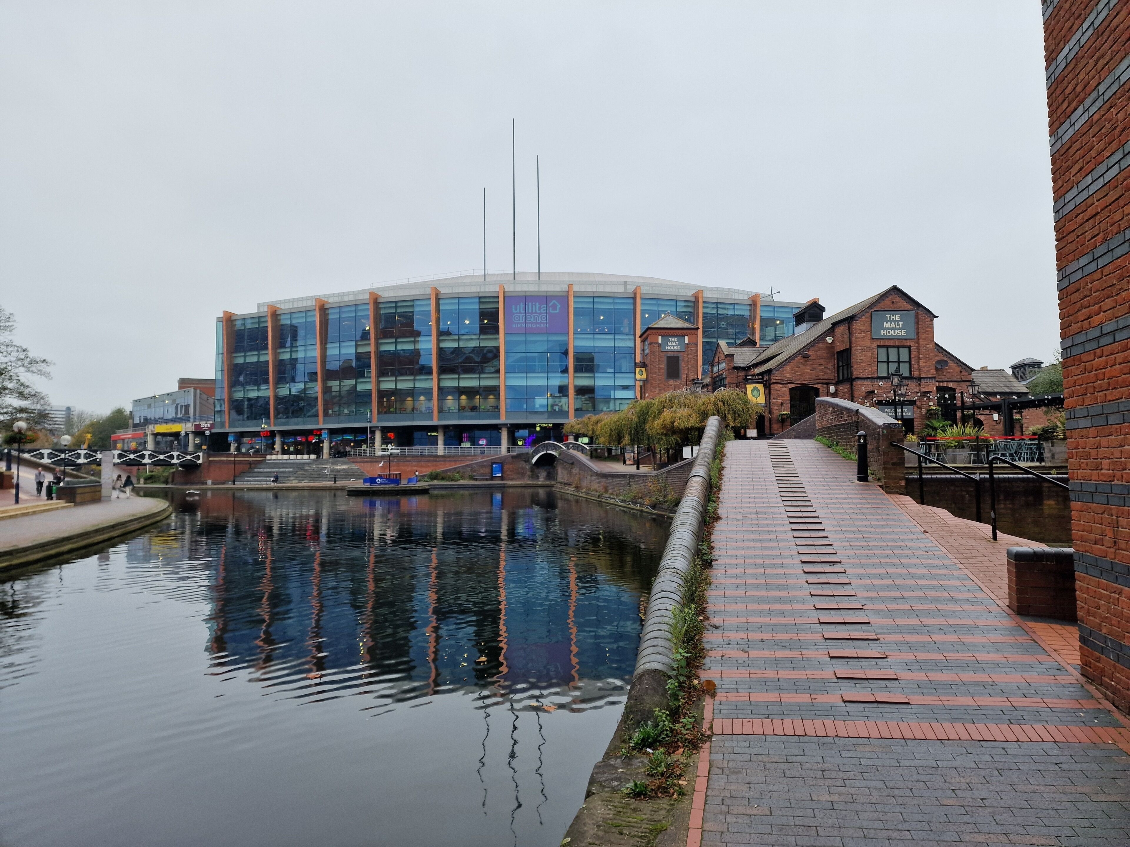 Un bâtiment moderne doté d’une façade en verre, d’un canal et d’un chemin bordé de briques.