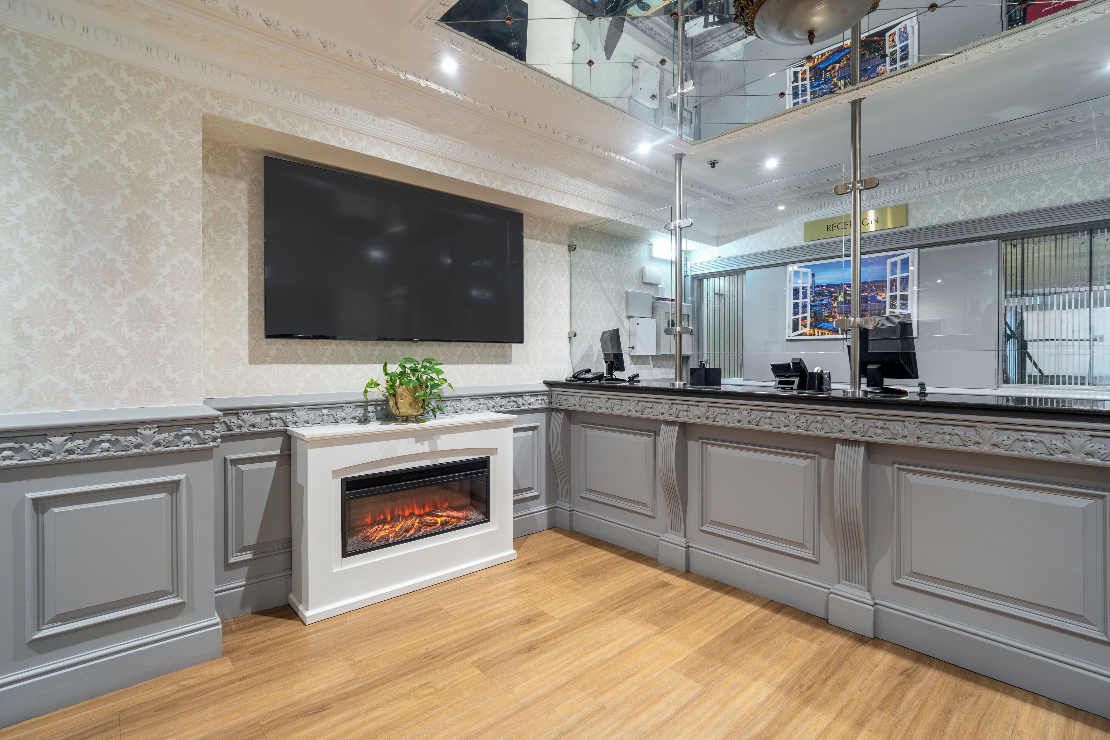 A modern kitchen with a built-in fireplace, a large flat-screen TV, and a view of the city through a window.