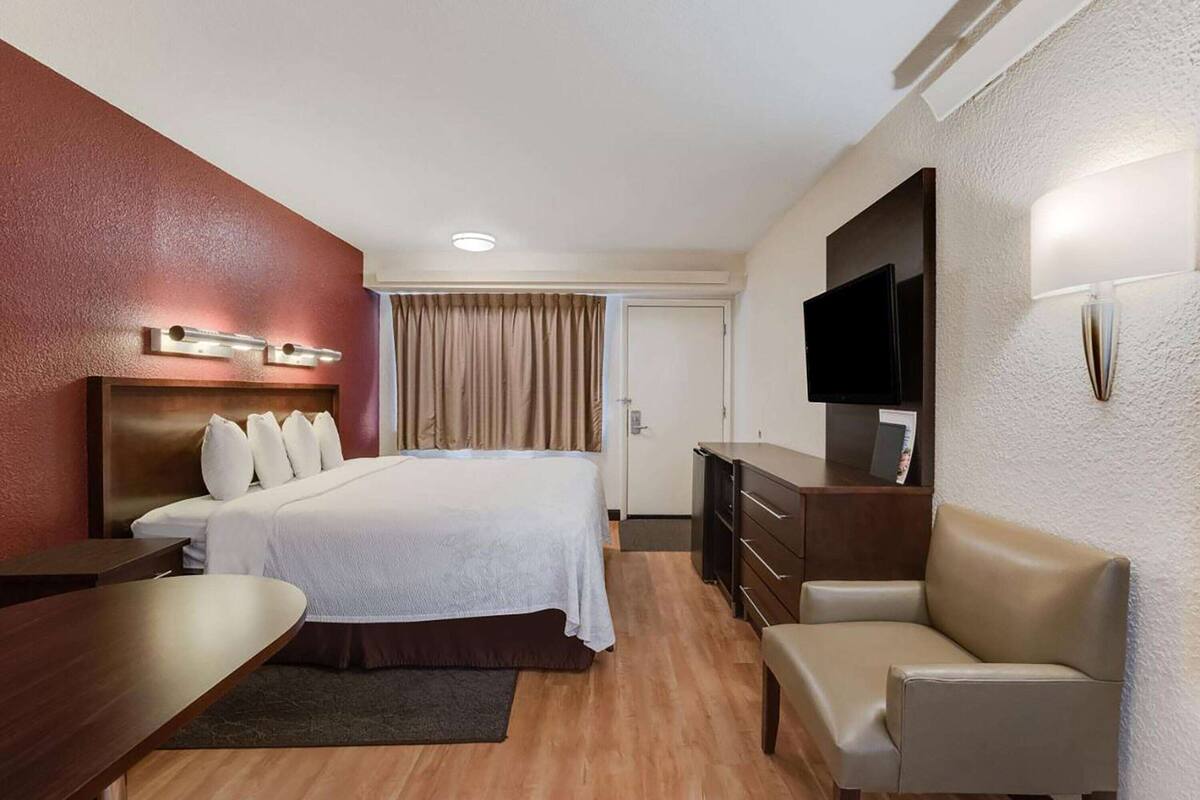 Une chambre d’hôtel comprenant un lit, un bureau, une chaise, une télévision et une commode.
