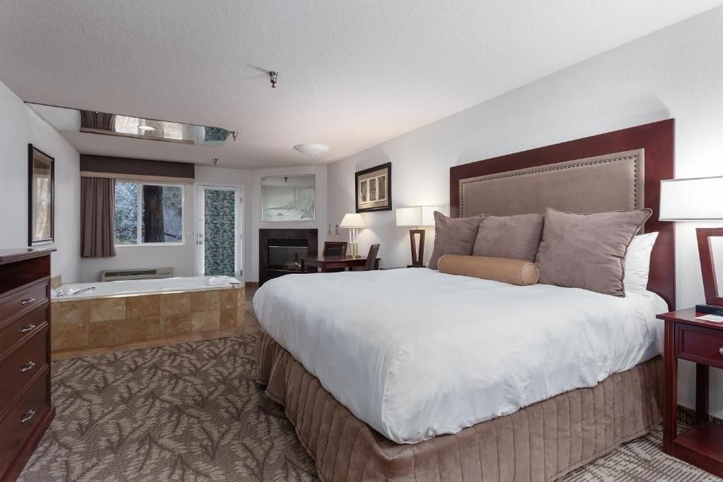 A hotel room with a large bed, a bathroom with a bathtub, a desk, and a chair.
