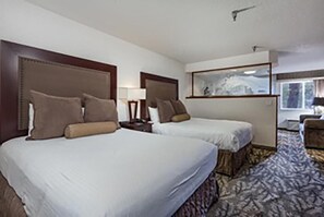 A hotel room with two beds, a large window, and a carpeted floor.
