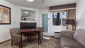 Una habitación con una mesa de comedor, dos sillas, un sofá, una lámpara y una puerta con ventanal.