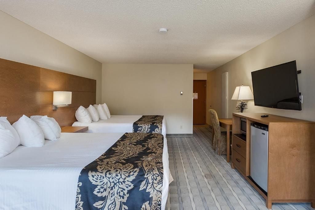 A hotel room with two beds, a desk, a television, and a wardrobe.