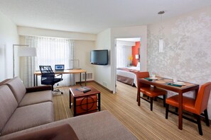 A hotel room with a sofa, a desk with a computer, a TV, a dining table with chairs, and a bed. - PrimeStay Extended Suites by IHG (Madison)