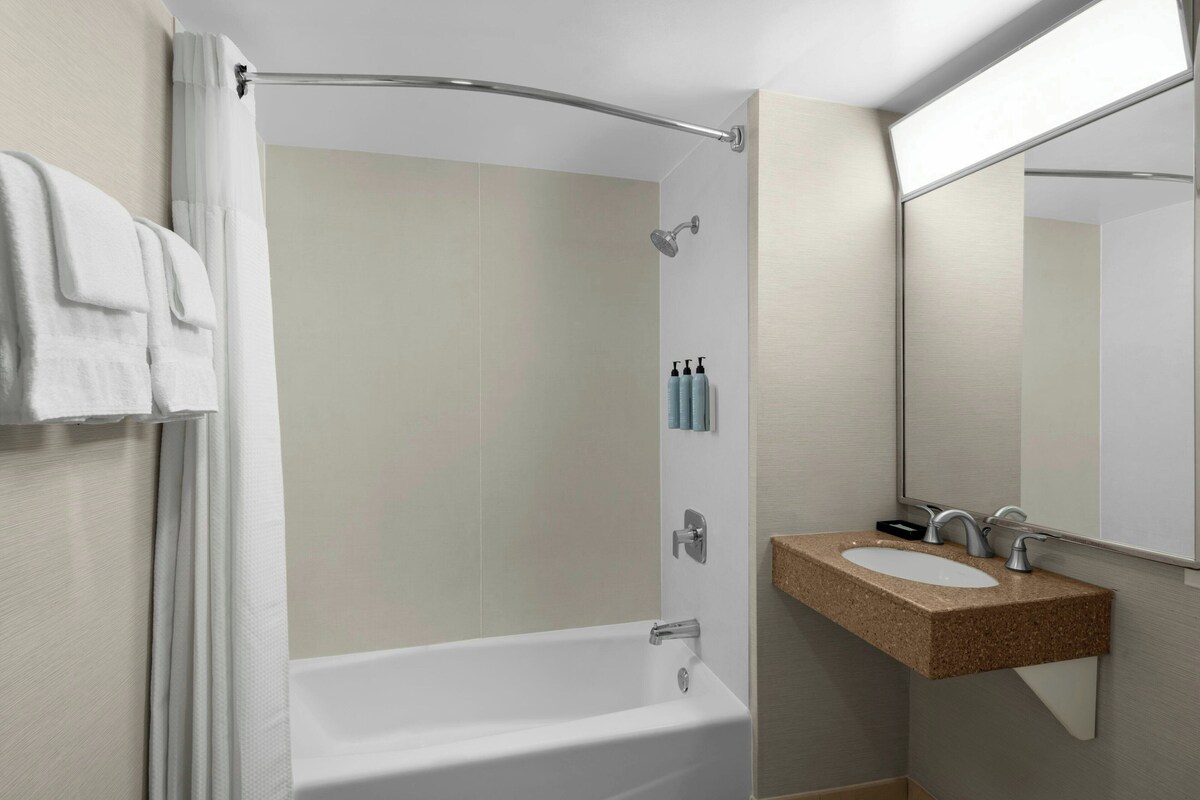 A modern bathroom with a freestanding bathtub, a vanity with a mirror, and a shower area.
