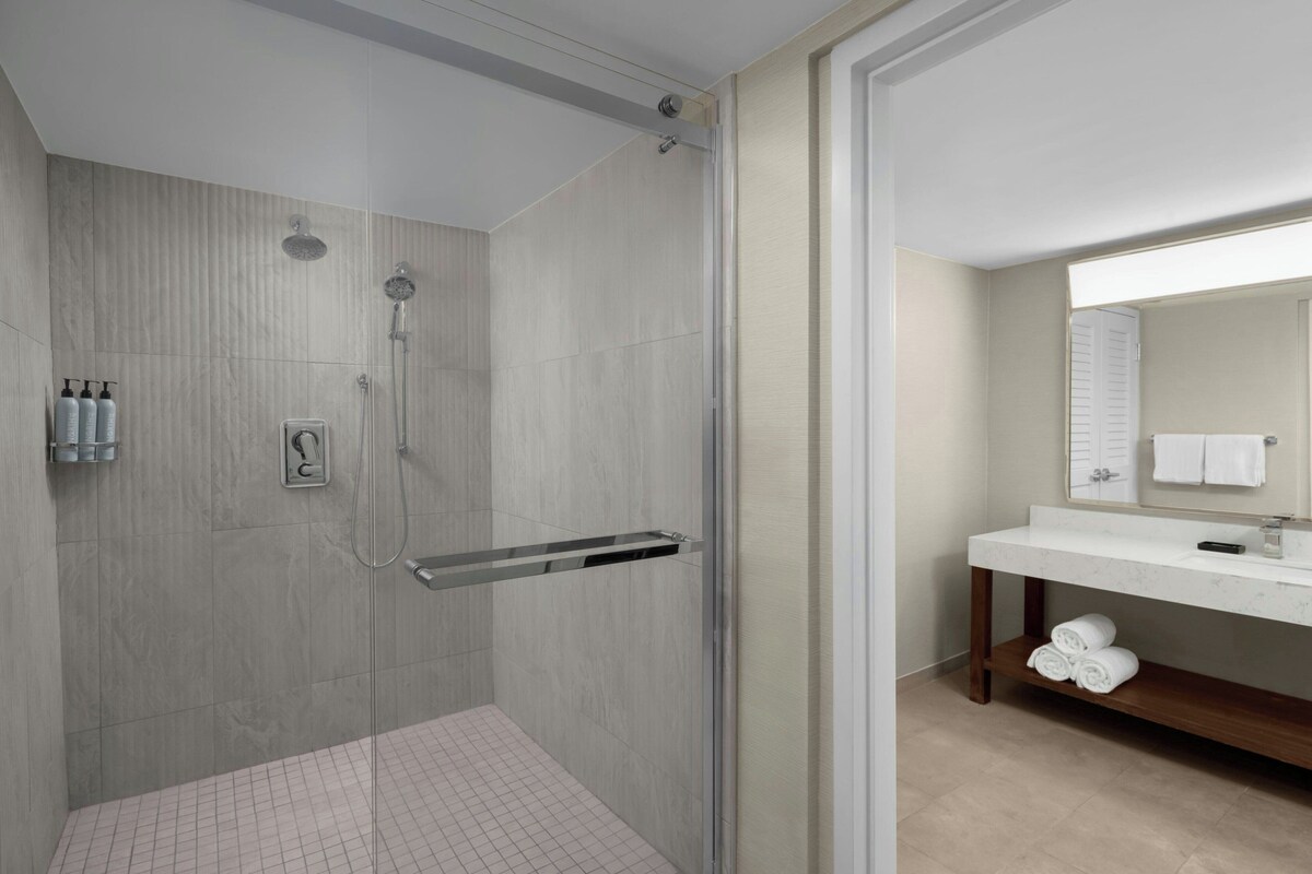 A modern bathroom with a shower, a vanity with a mirror, and a towel rack.