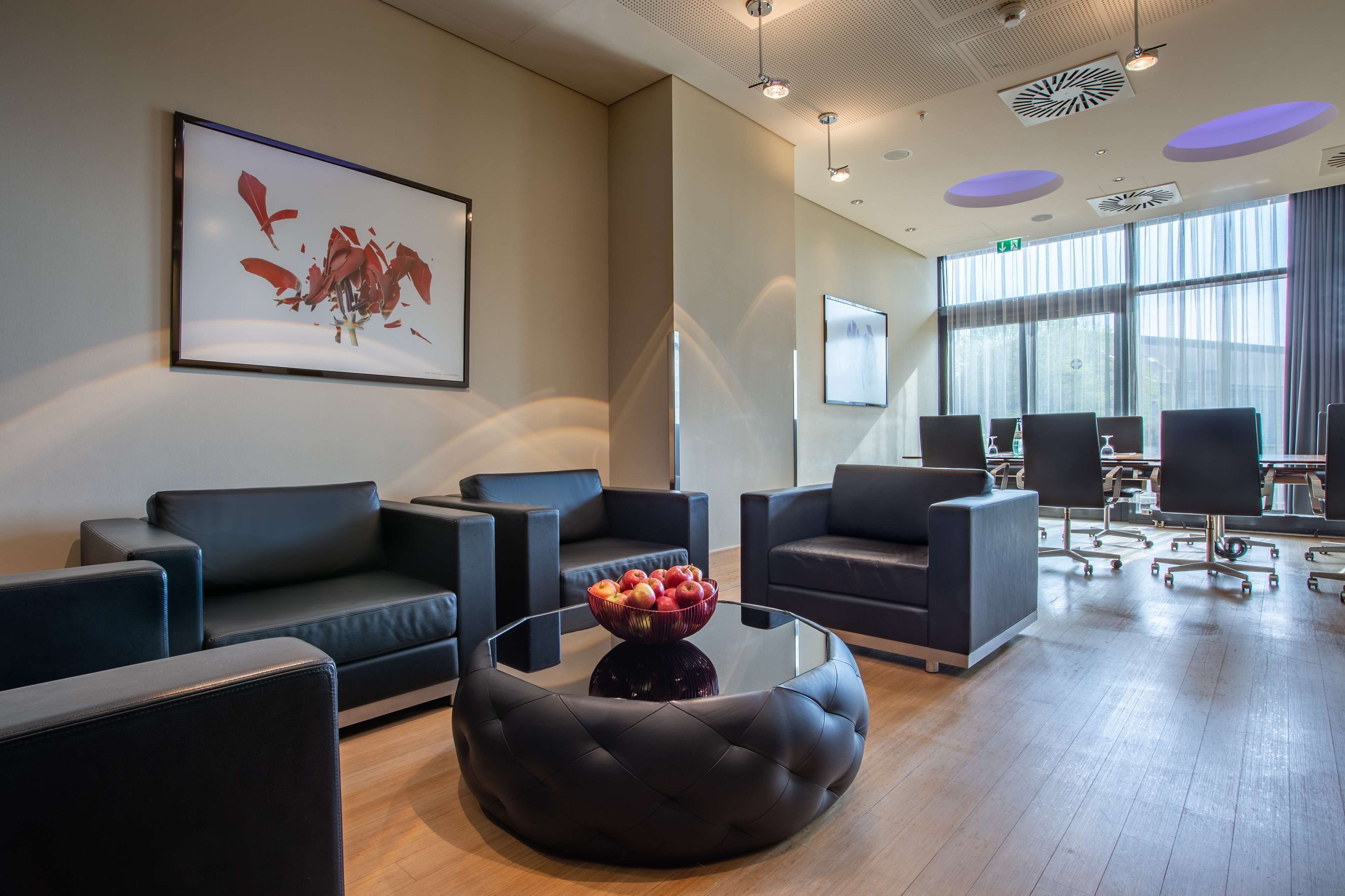 Eine moderne Lobby mit Ledersofas, einem Glastisch mit Früchten und großen Fenstern.