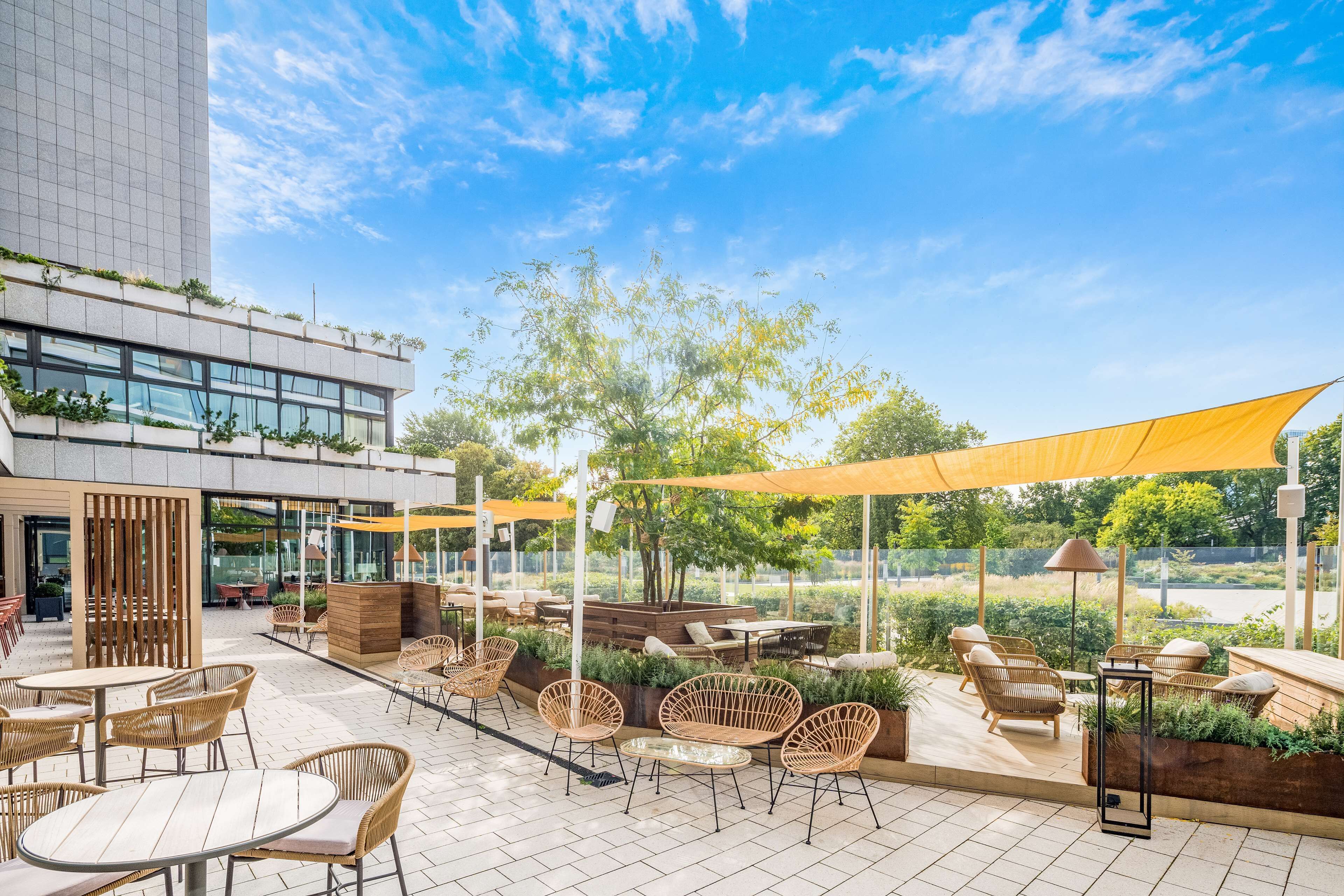 An outdoor patio area with wicker furniture, a wooden deck, and a view of a modern building.