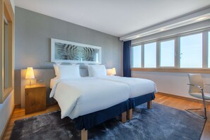 A modern hotel room with a large bed, two bedside tables with lamps, a chair, a large window, and a framed artwork on the wall. - Radisson Blu Hotel, Hamburg (Hamburg)