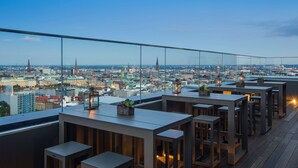 Eine Dachterrasse mit Tischen und Stühlen, die einen weiten Panoramablick auf die Stadt bietet.