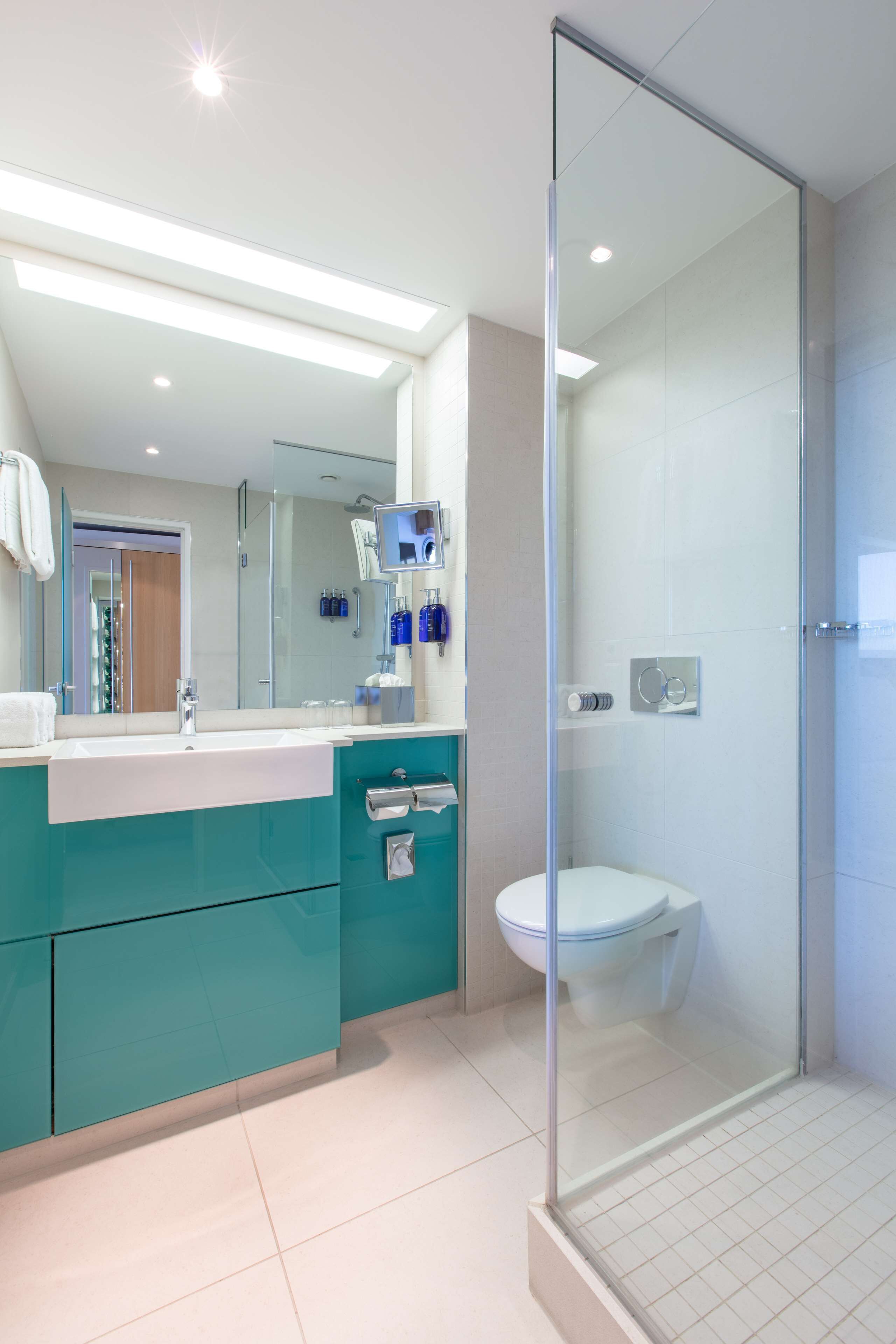Une salle de bain moderne avec une douche à parois de verre, un lavabo avec un miroir et des toilettes.