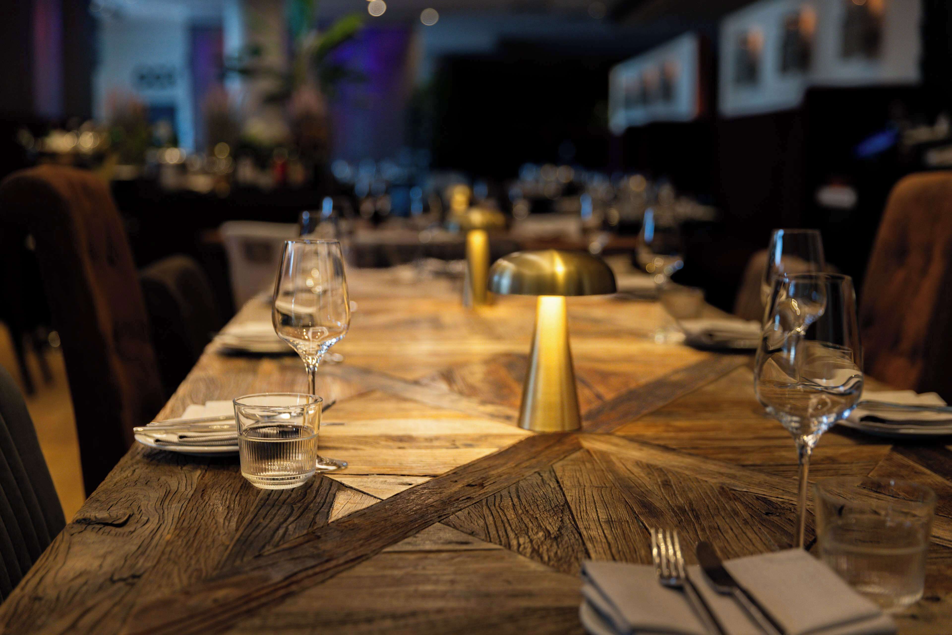 Une table de restaurant mise avec des verres à vin, des verres à eau et des couverts.