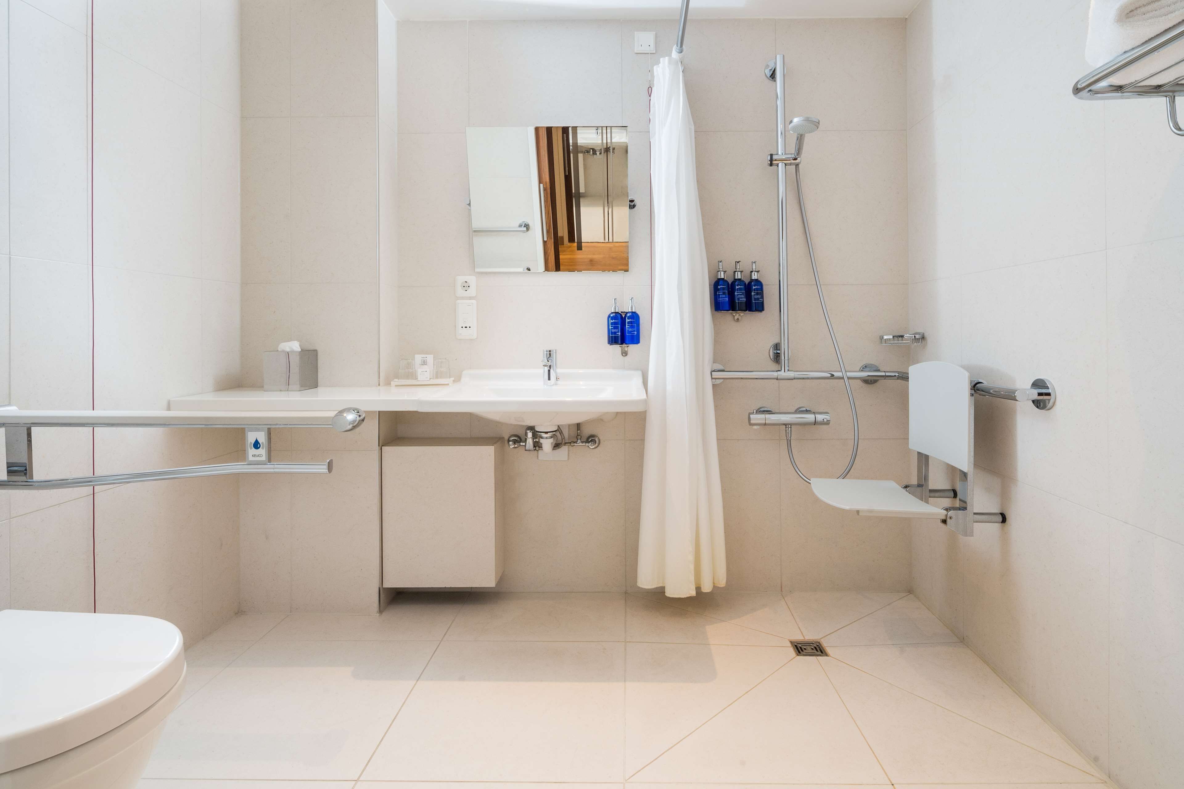 Een moderne badkamer met een witte wastafel, spiegel en douche.