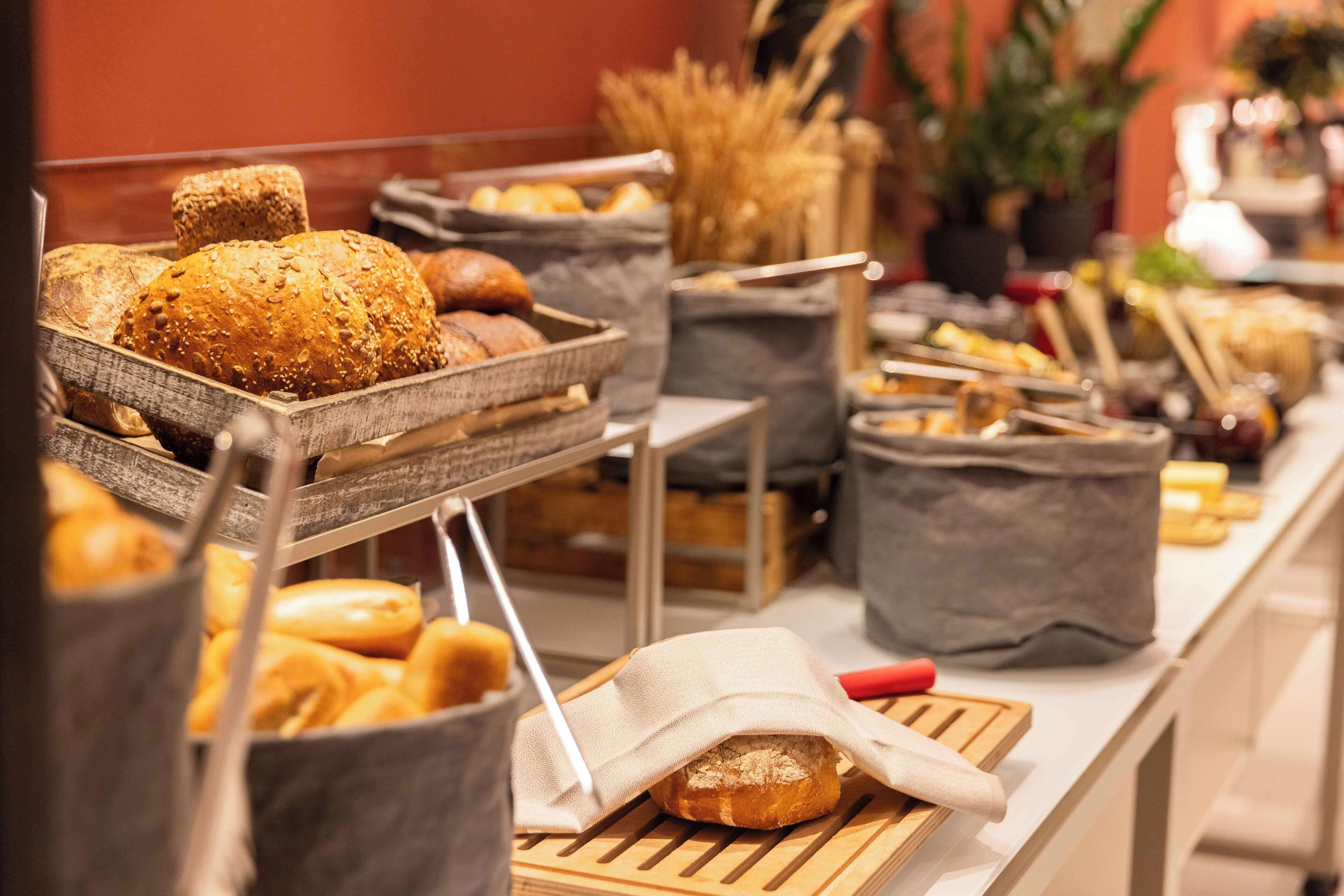 A buffet with various breads and pastries displayed in baskets and containers.