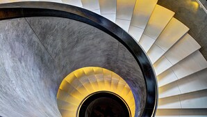 Eine Wendeltreppe mit einem zentralen, beleuchteten Bereich und einem gemusterten Boden.