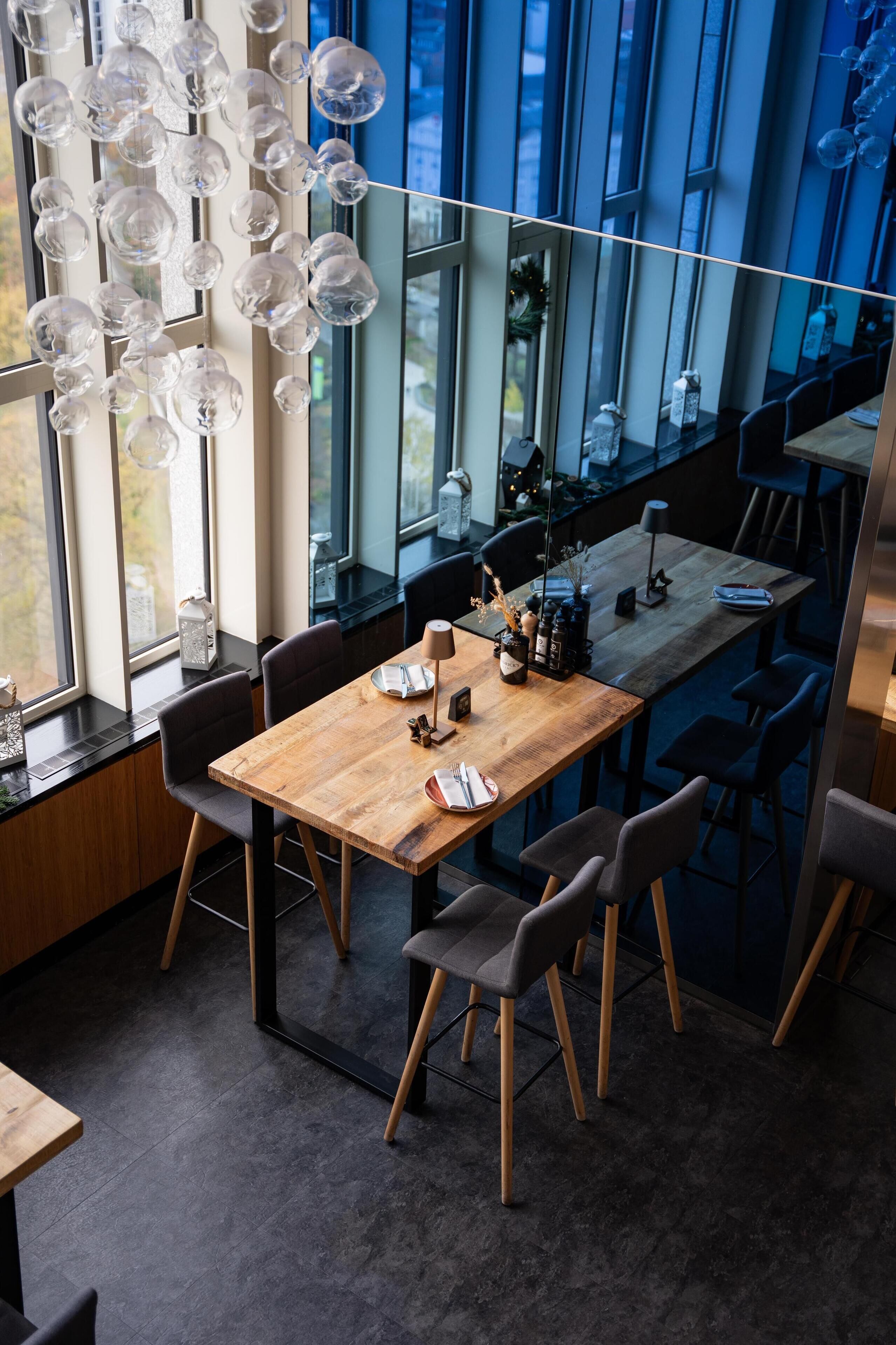 A modern dining area with a wooden table, chairs, and hanging glass orbs.