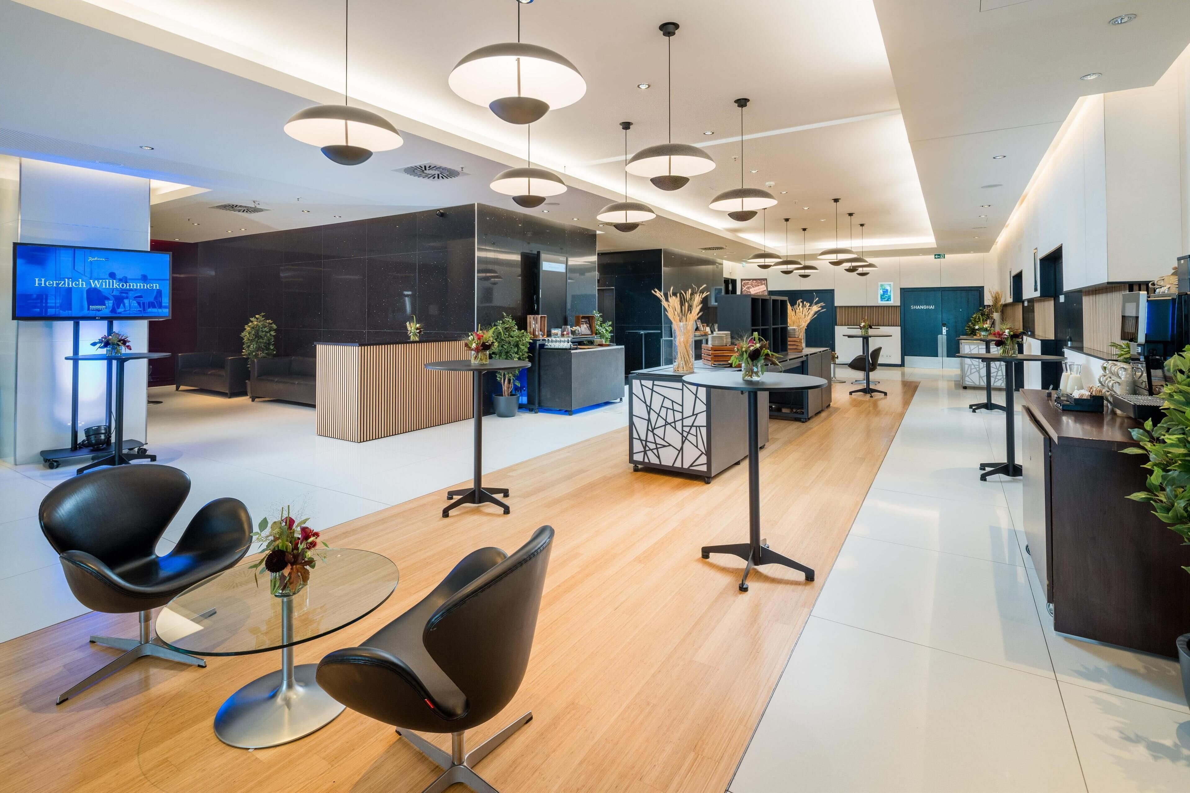 Un espace d’accueil moderne doté d’un téléviseur à écran plat, de chaises noires, d’un comptoir de réception et d’un plancher en bois.