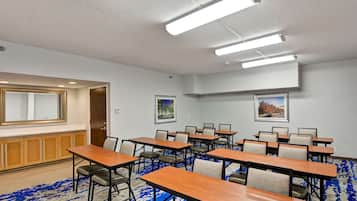 A conference room with multiple tables and chairs, a large mirror, and framed pictures on the walls.