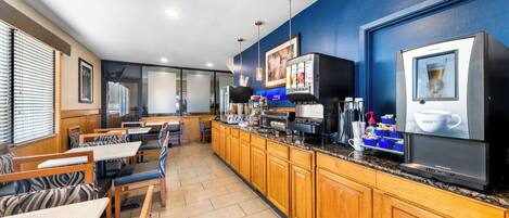 A modern kitchen with wooden cabinets, a coffee machine, and a large screen displaying a coffee advertisement.