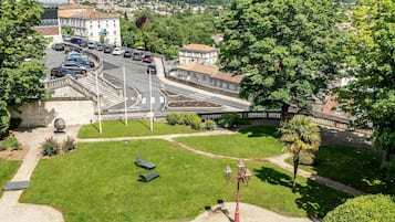 Um parque com uma passarela pavimentada, bancos e um lampião.