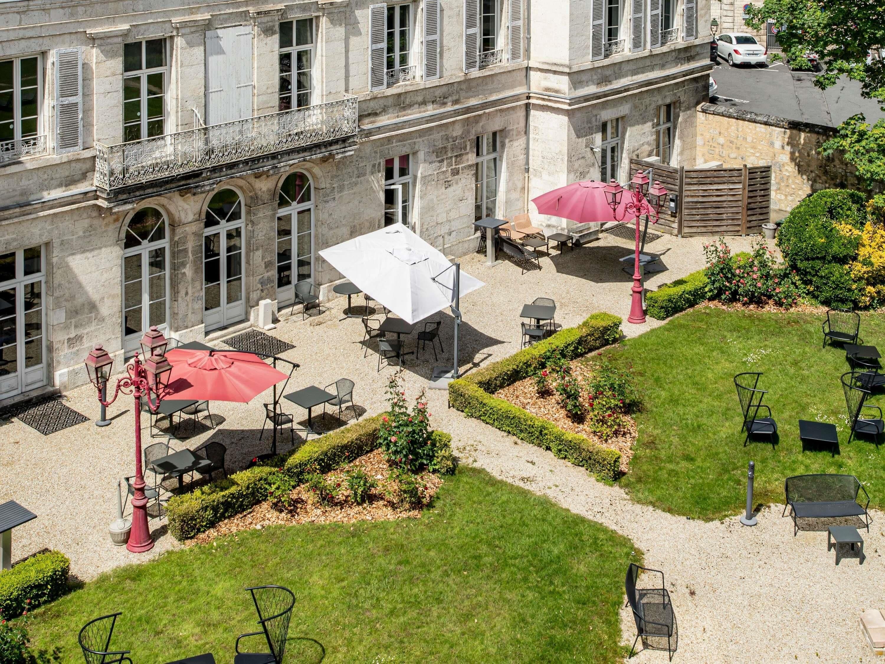 A courtyard with outdoor seating, stone building, and greenery.