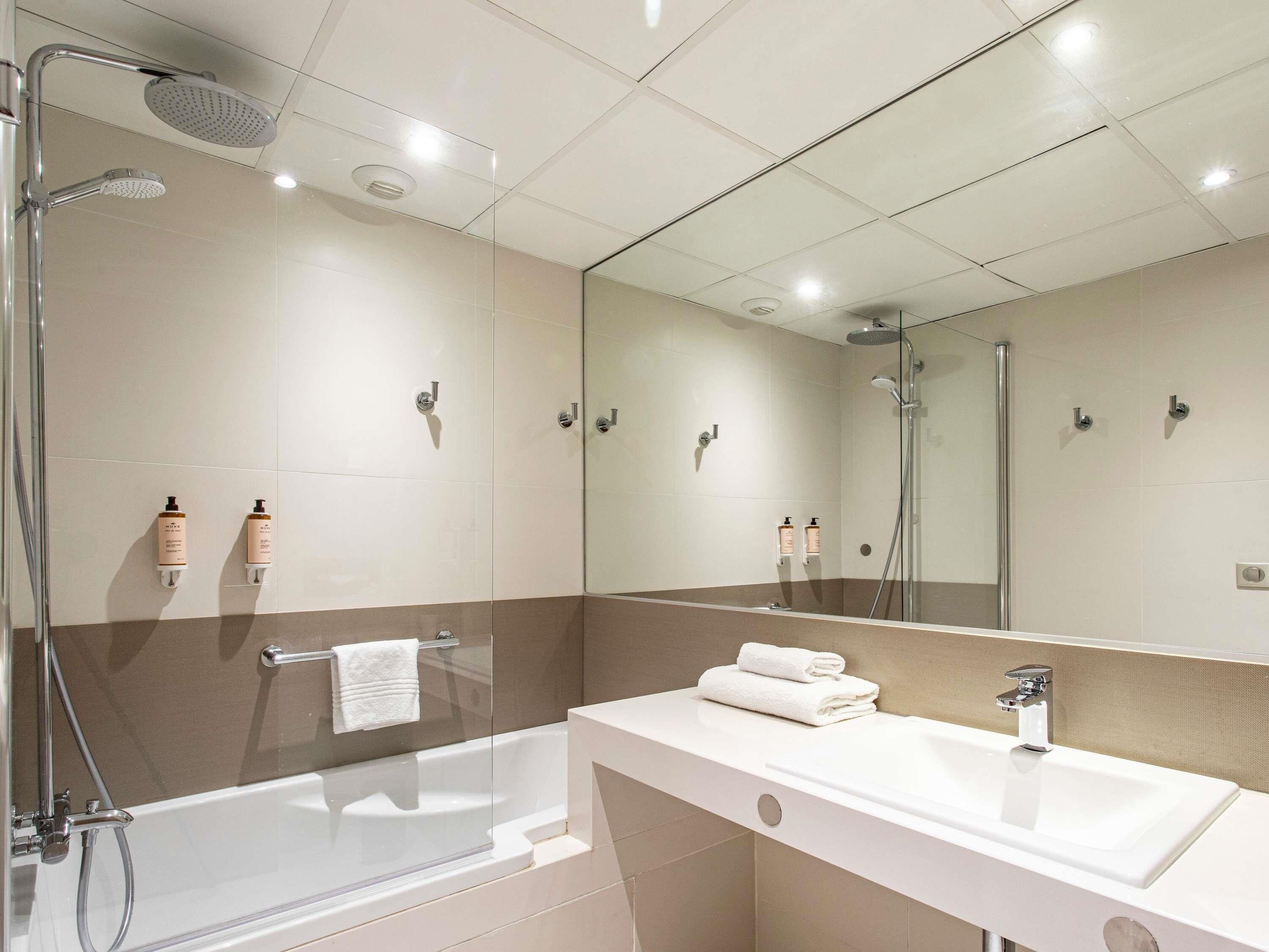 A modern bathroom with a bathtub, a shower area, and a vanity with a mirror.