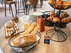 Un buffet de petit-déjeuner comprenant du pain, des croissants et des viennoiseries.