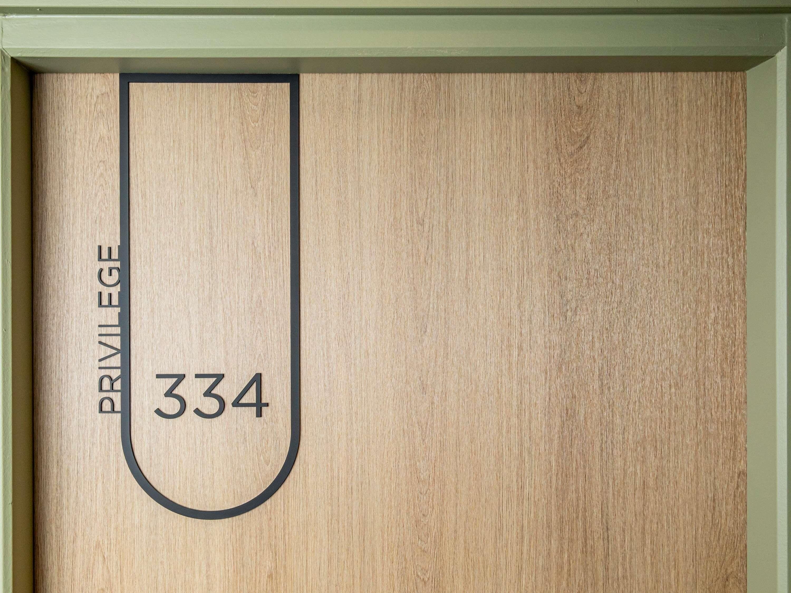 A wooden door with the text "PRIVILEGE 334" and a black outline of a letter 'U'.