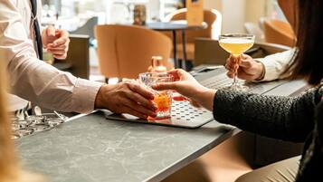 A bar setting with a marble countertop, glasses, and a person pouring a drink.