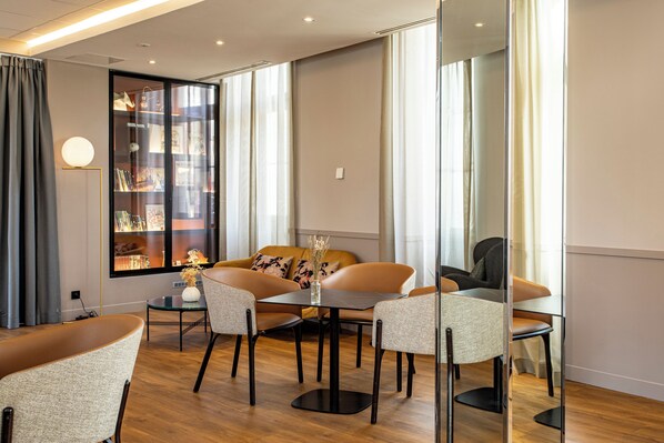 A modern living room with a sofa, chairs, a coffee table, and a bookshelf. - Mercure Angouleme Hotel de France (Angouleme)