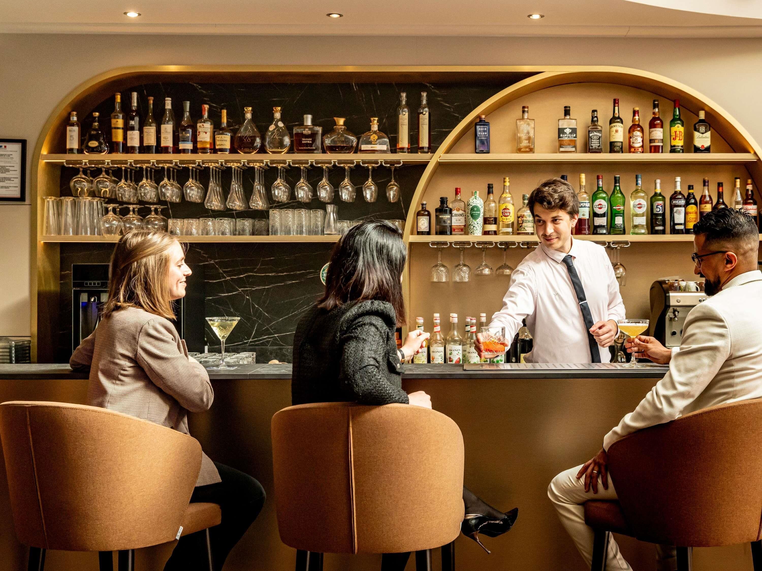 A bar area with multiple shelves of liquor bottles, glasses, and a bar counter.