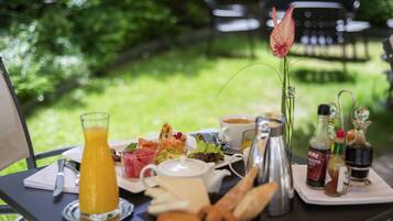 A breakfast table with a variety of food items, a coffee cup, and condiments.