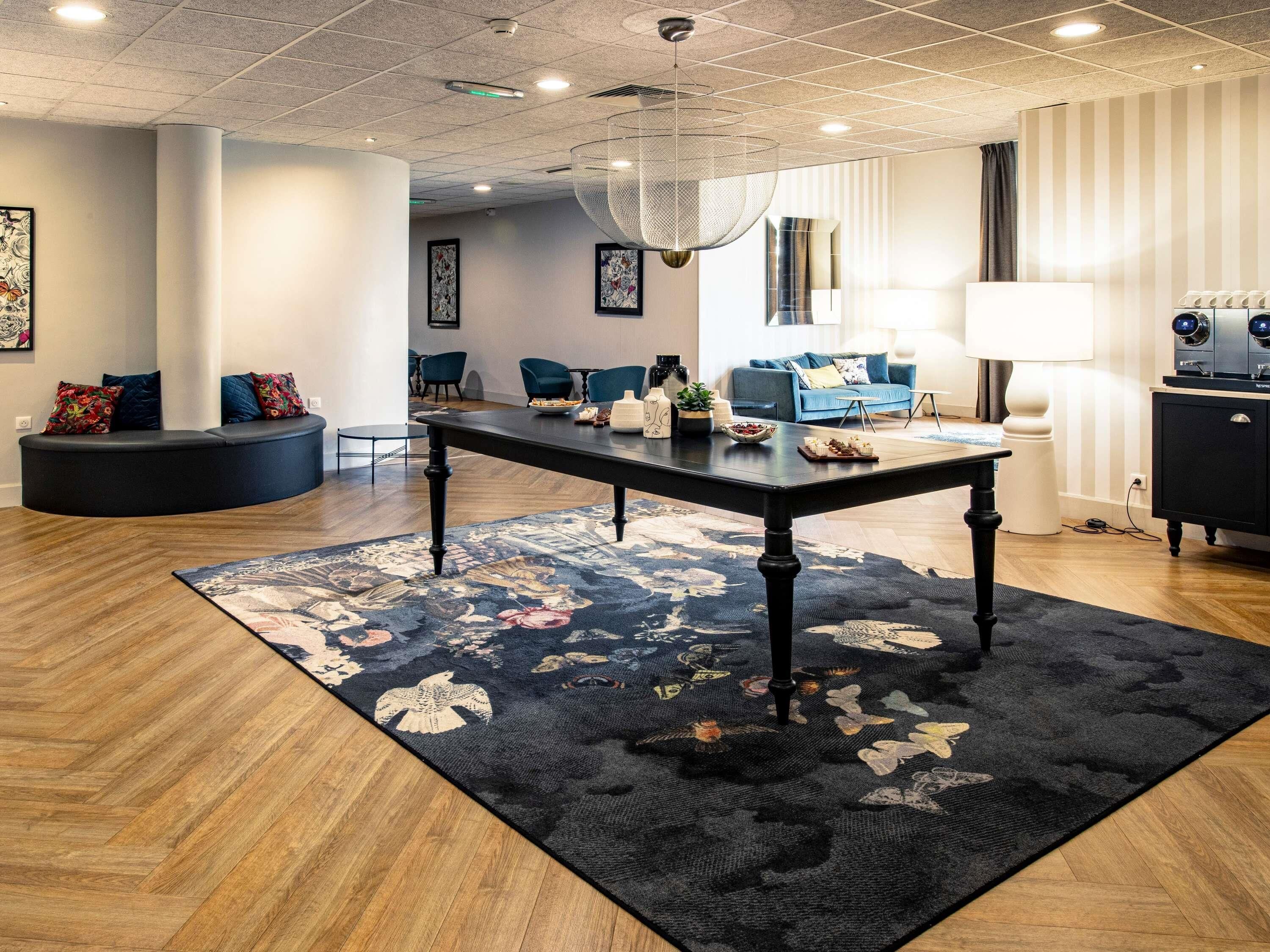 A modern interior with a central table, seating area, and a decorative rug.