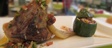 A plate with a lamb shank and stuffed zucchini.