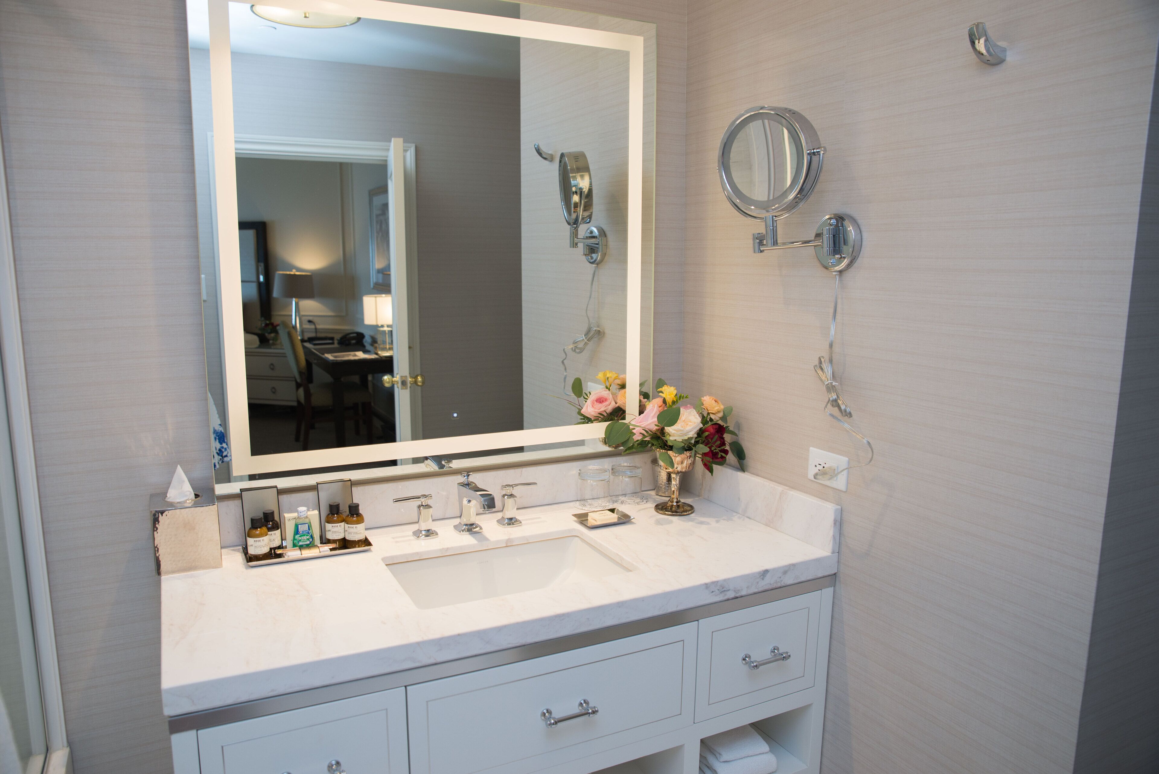 Un baño con un espejo grande, un lavamanos y un mueble tocador con cajones.