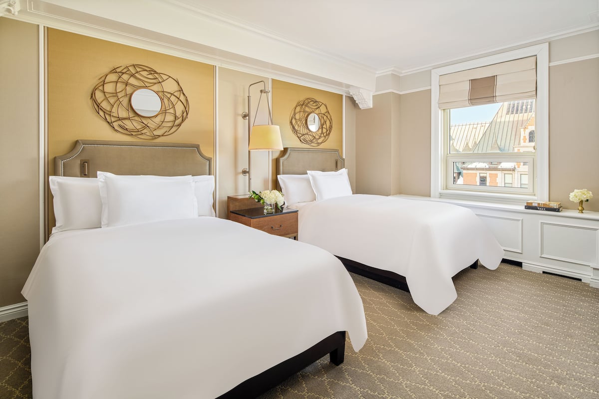 A hotel room with two beds, a large window, and decorative wall art.