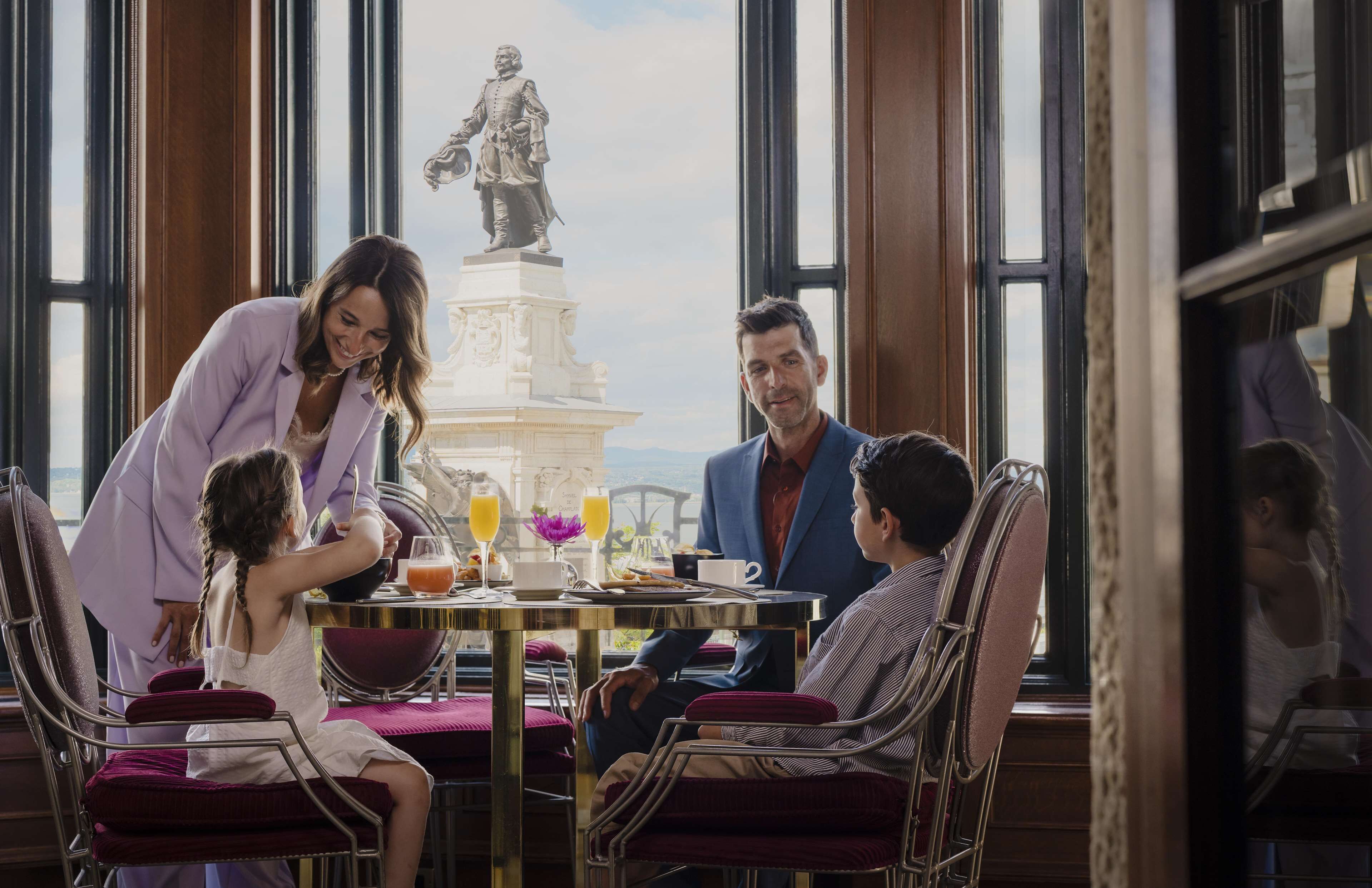 Una familia cenando en una mesa, con una estatua al fondo.