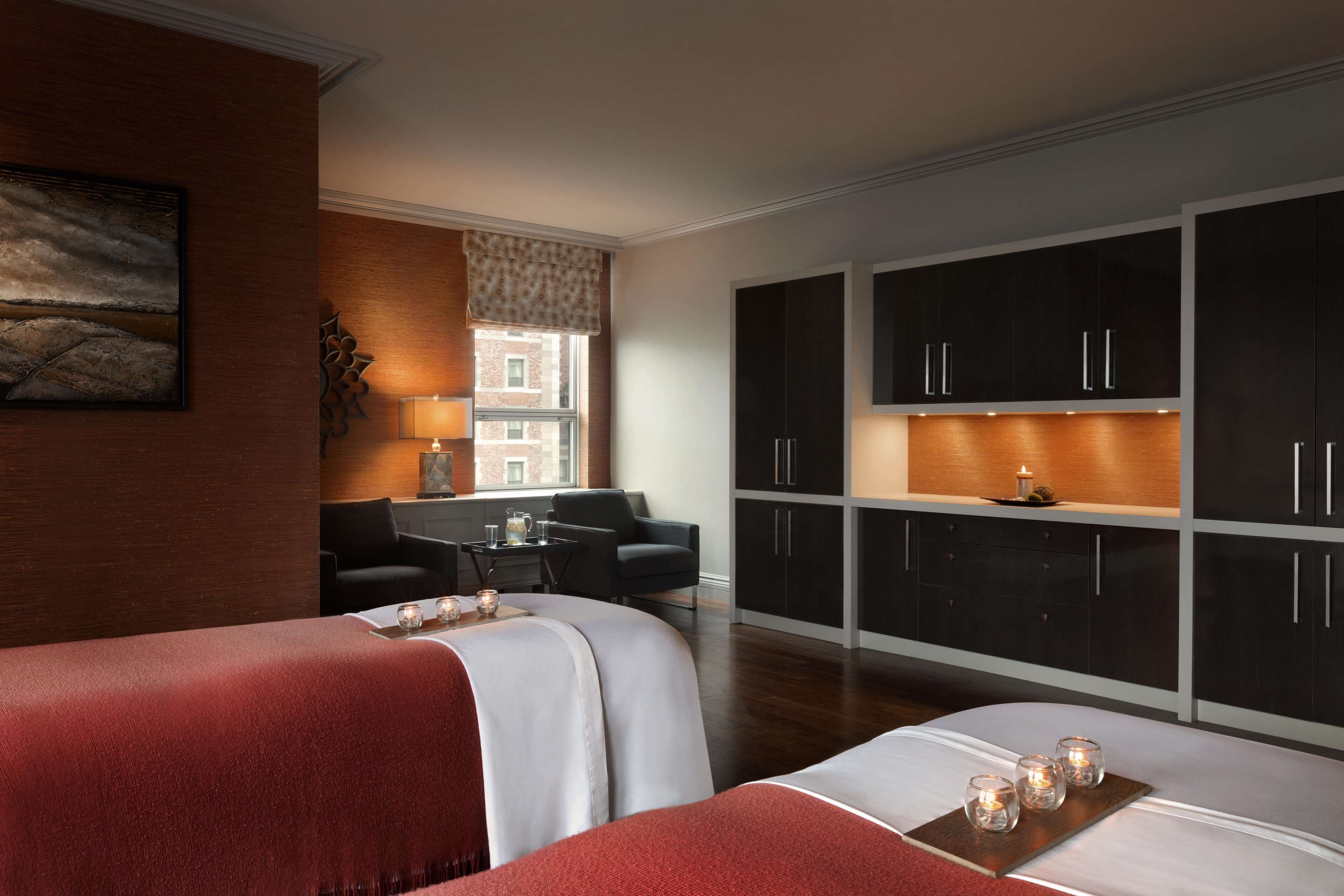A hotel room with two beds, a sitting area with a table and chairs, and a large wardrobe.