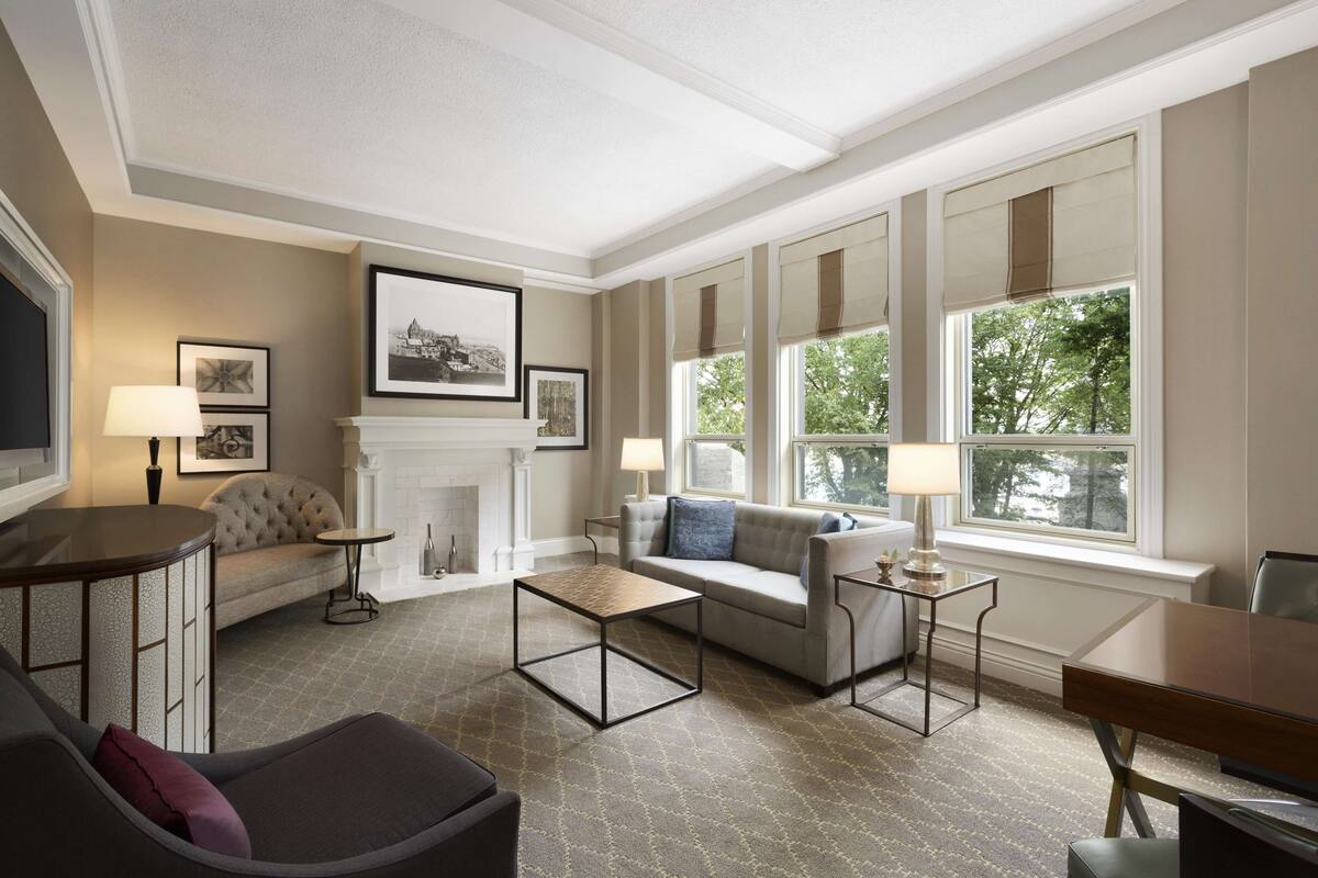 A spacious living room with a fireplace, comfortable seating, and large windows.