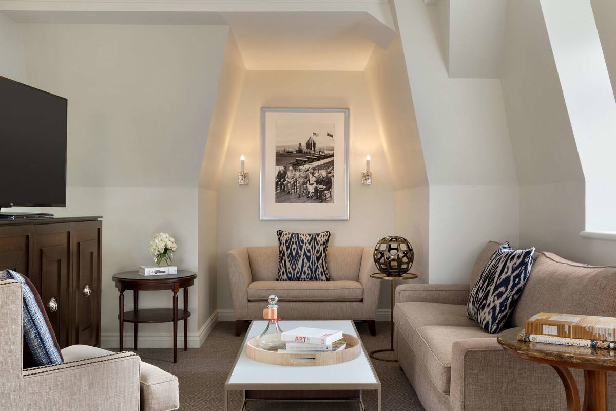A living room with a sofa, armchairs, a coffee table, and a television.