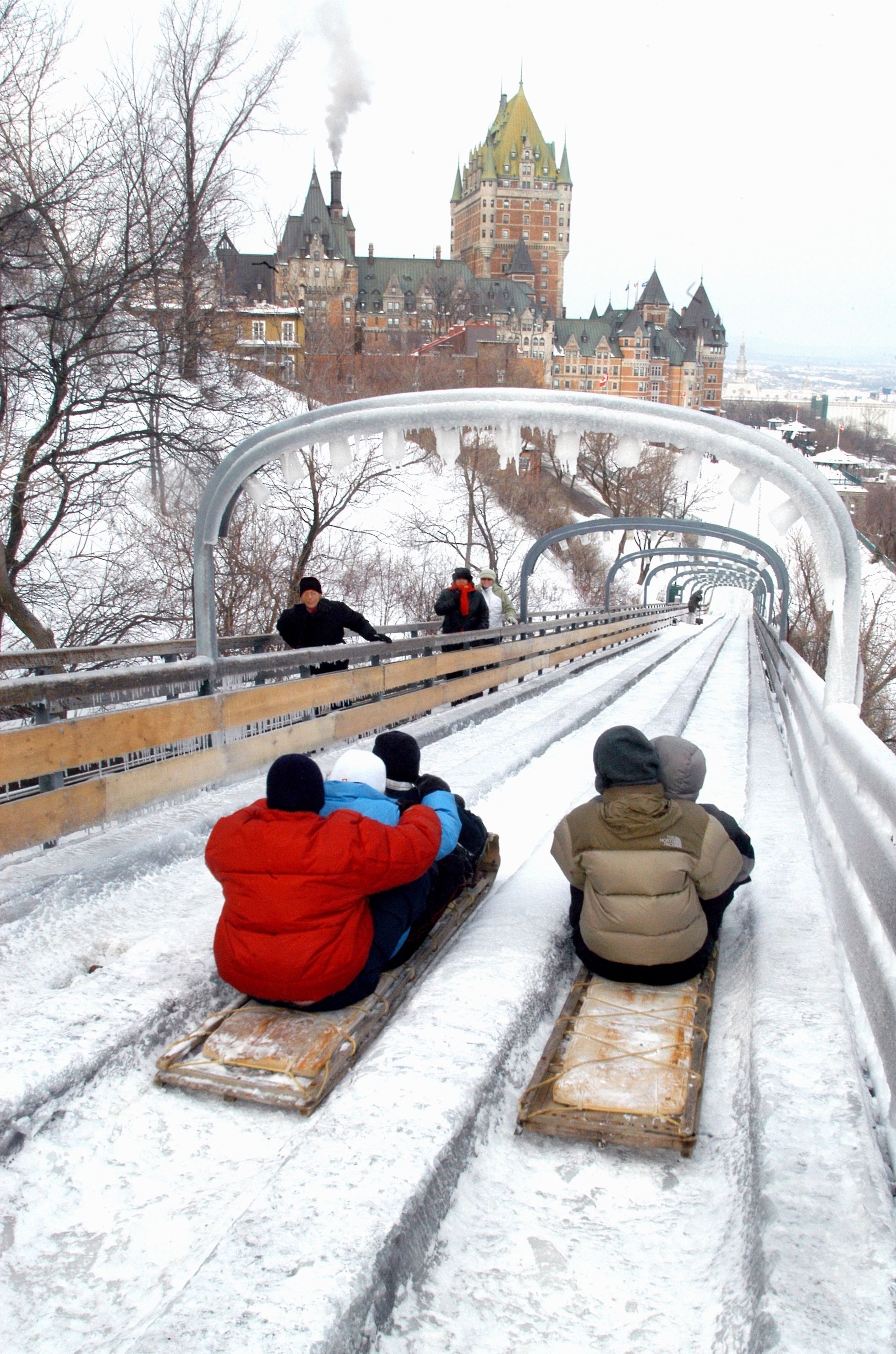 A snowy scene with people sledding on a wooden track.