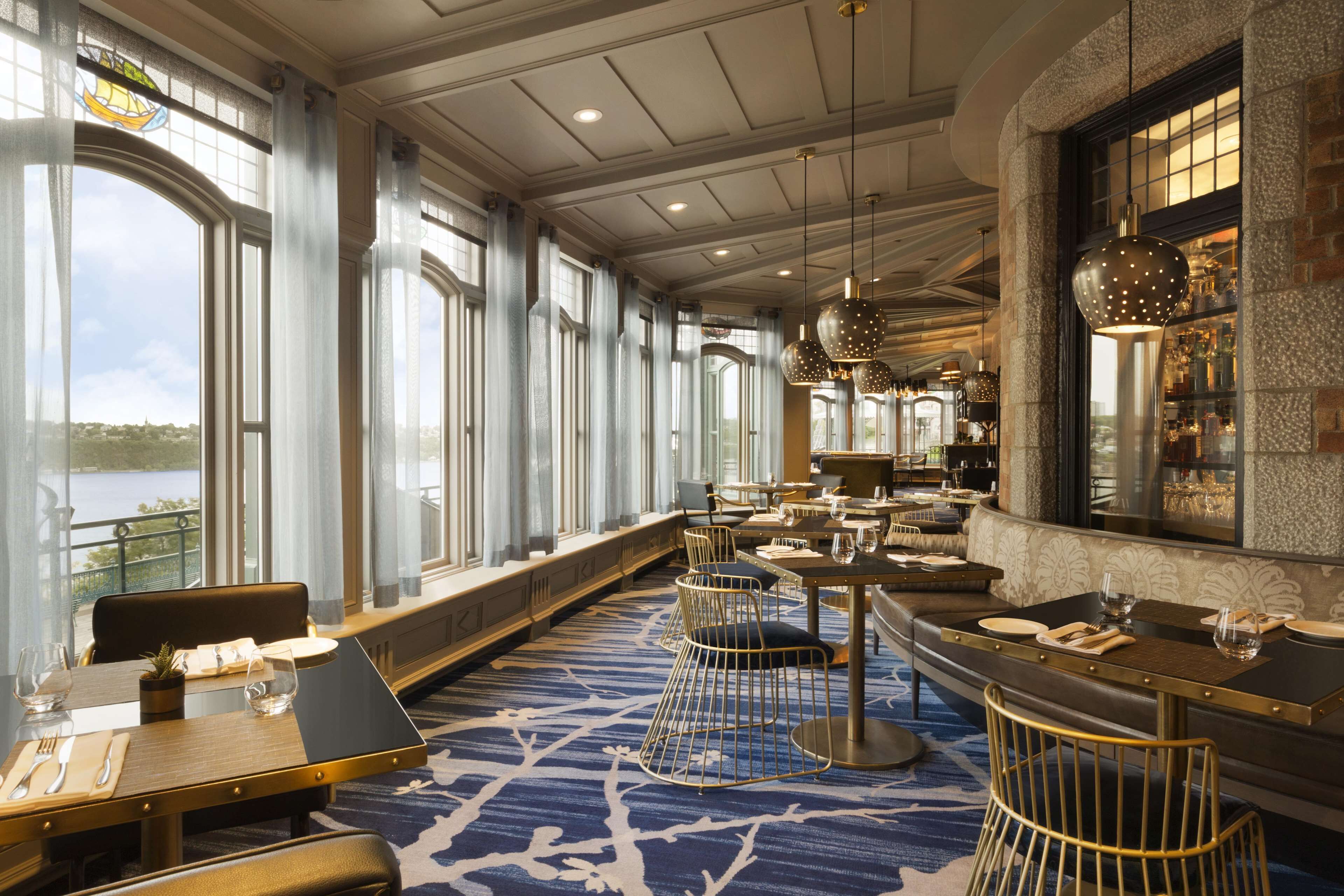 Un comedor con mesas y sillas, ventanas amplias y vistas al exterior.