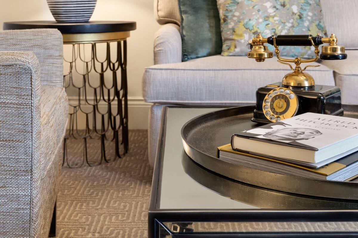 A modern living room with a sofa, a coffee table, a lamp, a vintage telephone, and a framed picture on the wall.