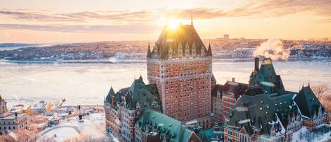 A historic building with a prominent tower, surrounded by snow-covered buildings and a river.
